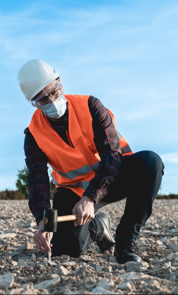 Engineer man doing topographic measures on land for construction work during coronavirus outbreak